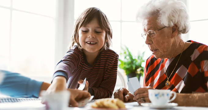 Young child and grandmother playing cards at table